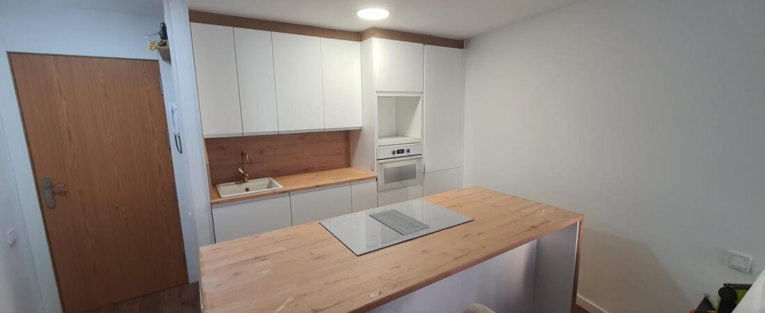 Cocina blanca con isla en apartamento de playa